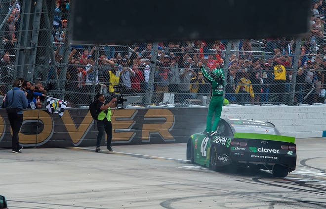 Kyle Larson stands on his car and waves to crowd after winning the NASCAR Cup Series playoff auto race Sunday, Oct. 6, 2019, at Dover International Speedway in Dover.