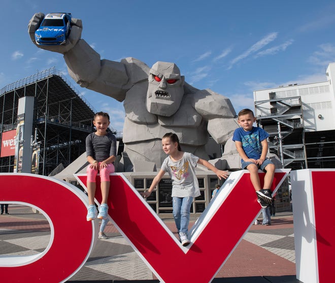 Piper Levkovski (6), left, of Smyrna, Del., Victoria Crowley (5), of Parlin, N.J., Corbin Levkovski (4), of Smyrna, Del., pose for a photos in front of Miles the Monster before the Drydene 400 - Monster Energy NASCAR Cup Series playoff auto race, Sunday, Oct. 6, 2019, at Dover International Speedway in Dover.