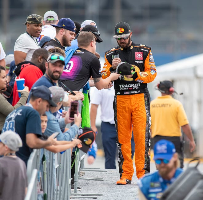 Martin Truex Jr., right, gives an autograph at the Drydene 400 - Monster Energy NASCAR Cup Series playoff auto race, Sunday, Oct. 6, 2019, at Dover International Speedway in Dover.