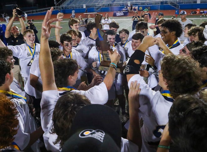 Salesianum players gather around the title trophy after Salesianum's 12-10 win in the DIAA state tournament championship game Thursday, May 27, 2021 at Dover High School.