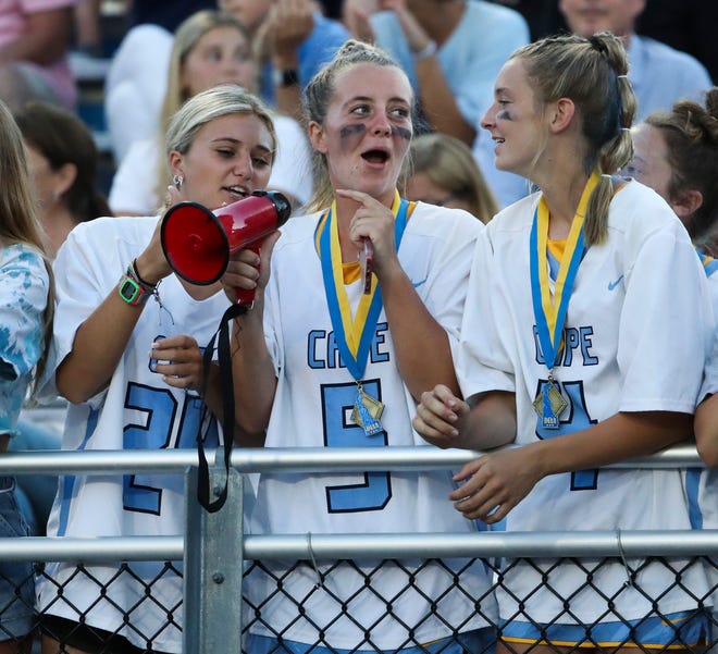 Cape Henlopen's girls' lacrosse members (from left) Alexi Nowakowski, Grace Wiggins and Elizabeth Rishko, fresh off their own title win on the neighboring field, cheer their counterparts in the first half of the DIAA state tournament boys' championship game Thursday, May 27, 2021 at Dover High School.