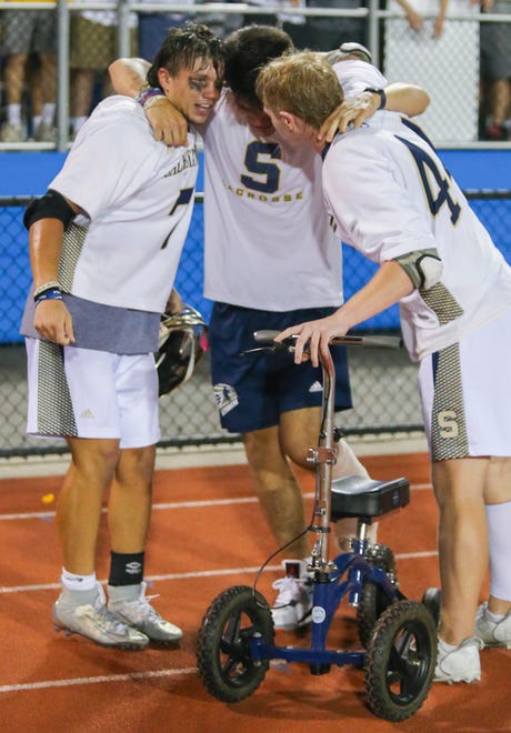 Salesianum's Chris Wong, sidelined with an injury, embraces Dylan Mooney (left) and John Gormley as Salesianum celebrates its 12-10 win in the DIAA state tournament championship game Thursday, May 27, 2021 at Dover High School.